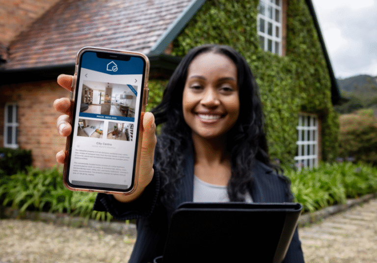 Real estate agent holding a smartphone displaying a home listing with photos and virtual tour features